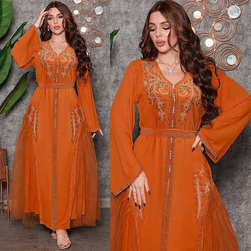 Model wearing a long-sleeved, orange diamond-embroidered dress with tulle panels and a matching belt.