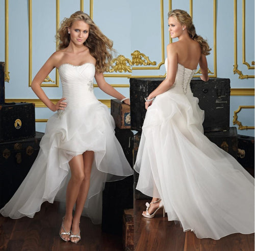 White strapless high-low wedding dress in organza with a draped bodice and ruffled skirt.