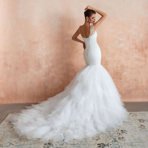 Back view of a white lace mermaid wedding dress with lace-up back and ruffled tulle train.