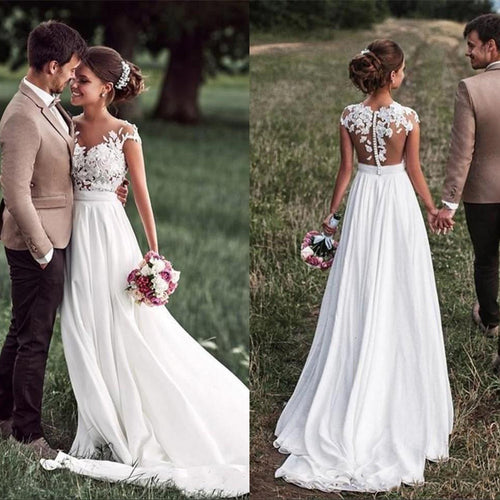 Bride in white chiffon dress with lace bodice, holding a bouquet, walking with groom.