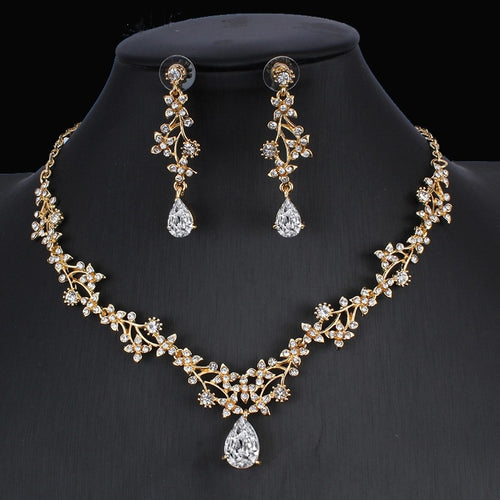 Gold jewelry set with leaf-like design and clear cubic zirconia stones, including a necklace and dangling teardrop earrings.
