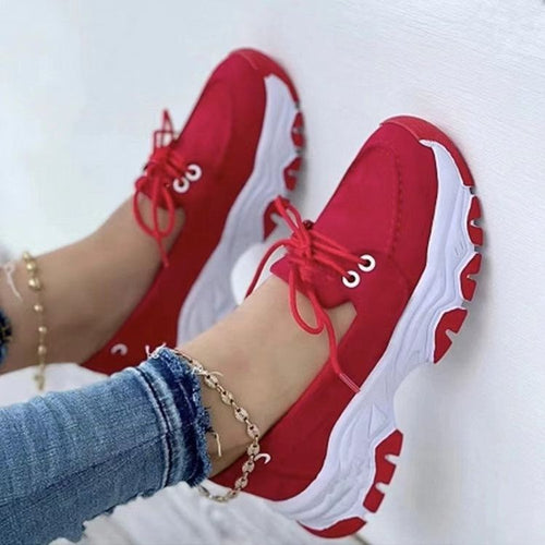 Red chunky lace-up shoes with thick white platform soles worn on feet.