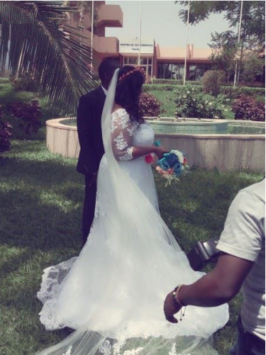 Bride wearing a long, sheer white veil outdoors, featuring a cascading lace-trimmed train.