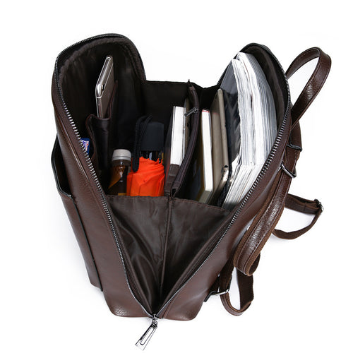 Open dark brown leather backpack filled with compartments holding a phone, umbrella, and papers.