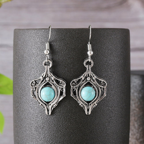 Silver-toned hook earrings featuring ornate metalwork framing a round turquoise gemstone.