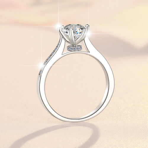 Silver ring with a large round solitaire stone and pavé band on a soft beige background.