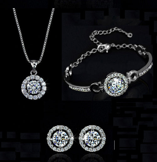 Silver jewelry set with necklace, bracelet, and earrings, featuring round crystal halos around large center stones.