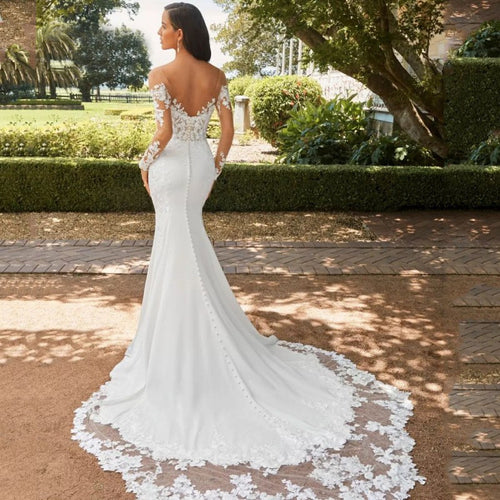 White fishtail lace wedding dress with sheer long sleeves and a buttoned back, ending in a long train.