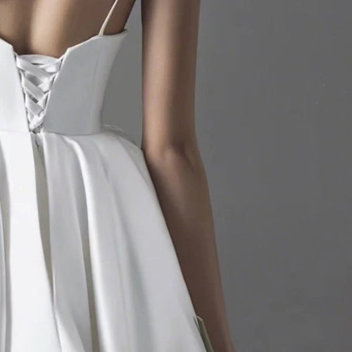 Back view of a white satin wedding dress with a lace-up corset back and thin straps.