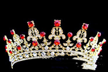 Gold tiara with sparkling clear crystals and vibrant red gemstones in an ornate, curved design against a black background.