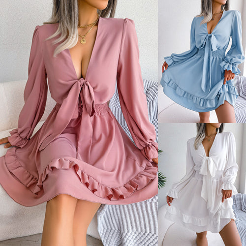 Three women wearing long-sleeve mini dresses with V-necklines, front ties, and ruffled hems in pink, blue, and white.