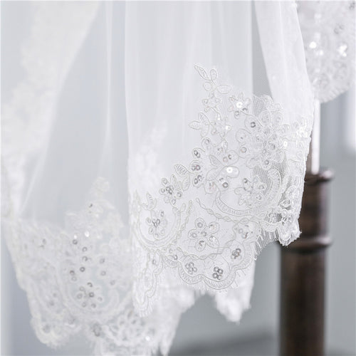 Ivory lace veil with subtle sequins, featuring delicate floral embroidery along the scalloped edge.