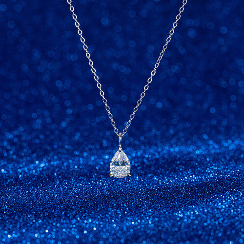 Sterling silver necklace with a teardrop-shaped gemstone pendant against a sparkling blue background.