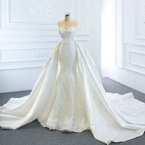 White strapless mermaid wedding dress with lace overlay and detachable satin overskirt on a mannequin.
