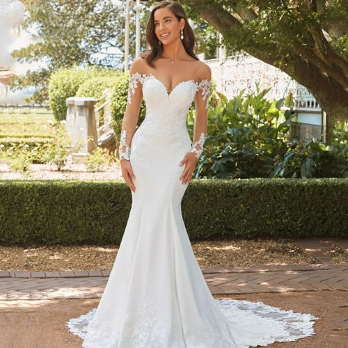 White lace fishtail wedding dress with sheer long sleeves and sweetheart neckline outdoors.