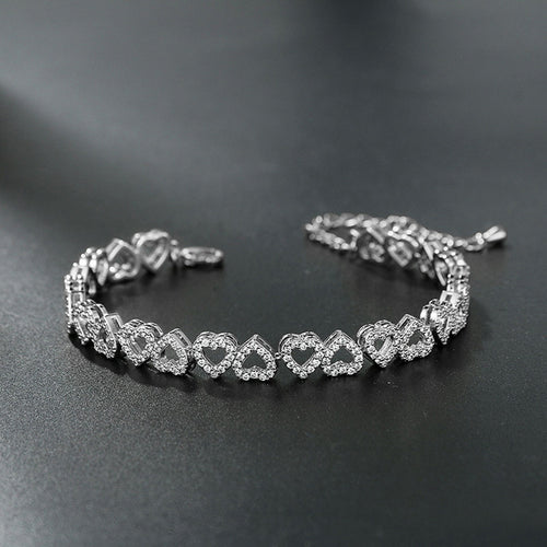 Silver-colored tennis bracelet with interlocking heart-shaped links, paved with small sparkling stones.