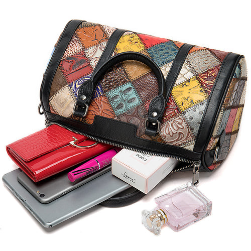 Colorful patterned leather barrel bag with black handles and zipper, containing a red wallet, phone, cosmetics, and perfume.