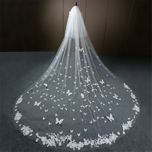 White tulle wedding veil with scattered 3D butterflies and lace flowers along the hem.