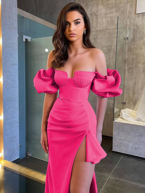 A model wears a hot pink off-the-shoulder dress with a bustier top, voluminous sleeves, and a high slit.
