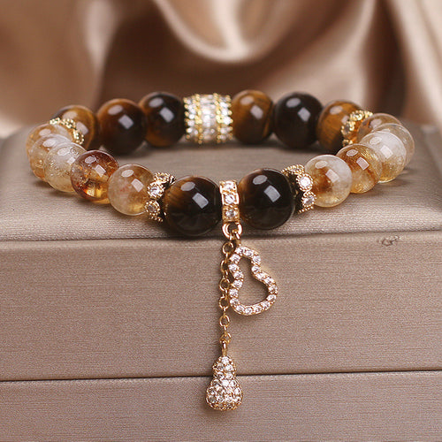 Beaded bracelet with yellow and brown stones, gold spacers, and a dangling gourd charm with crystals.