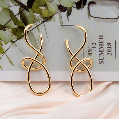 Gold metal hoop earrings featuring an abstract, intertwined loop shape.