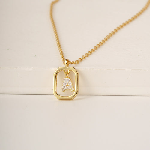 Gold chain necklace with a rectangular pendant framing a diamond-paved letter A.