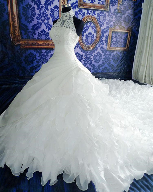 White ball gown wedding dress with lace halter neckline and voluminous ruffled skirt on a mannequin.